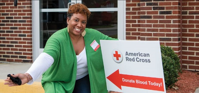 person poses next to sign advertising blood drive