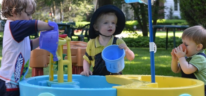 three toddlers play at a water table