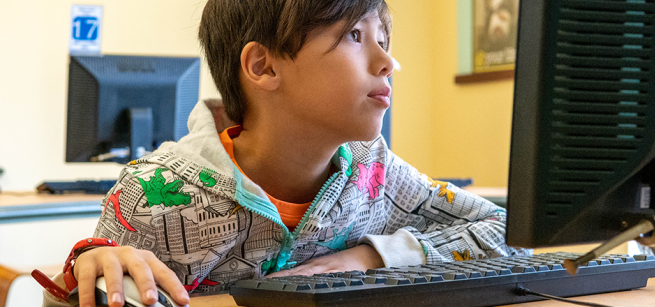 A boy using a desktop computer.