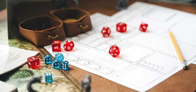 Red and blue dice scattered over a table full of papers, pencils, and a fantasy map
