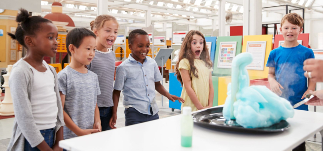 Children watching science demonstration of blue foam.