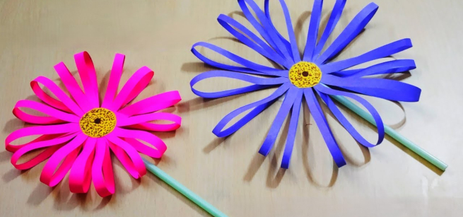 a pink paper sunflower and a blue paper sunflower with straw stems
