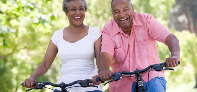 A happy, senior couple enjoys a bicycle ride.