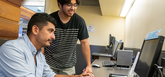 Two men working at a computer.