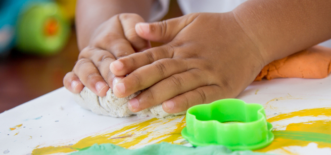 Child's hands squishing playdough.