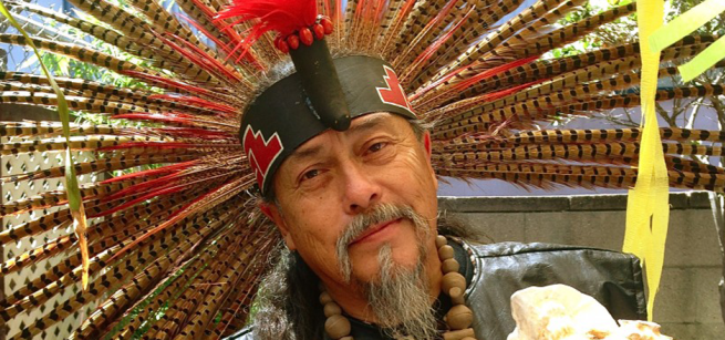 Face of musician Martin Espino with colorful feather head dress