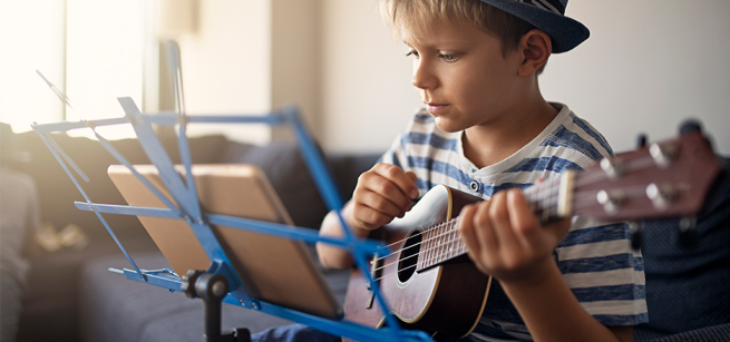 Boy playing a uke and reading music