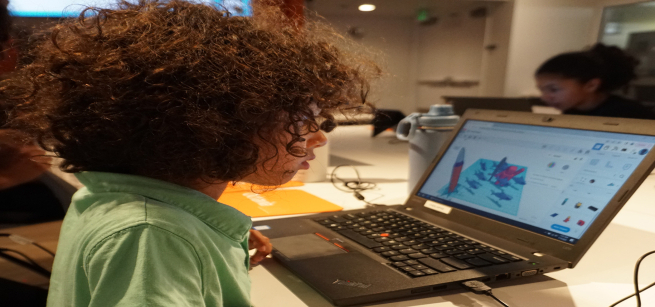 kid looking at a laptop in a library