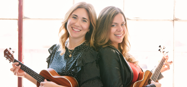 women standing back to back with ukeleles