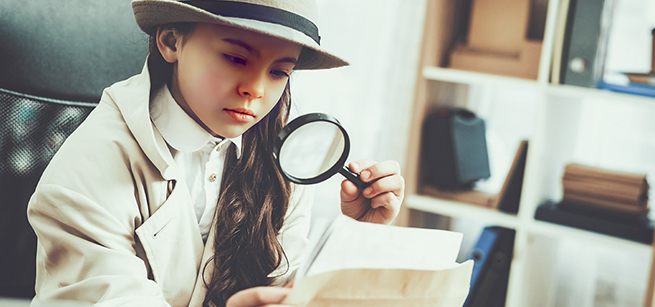 A girl dressed like a detective using a magnifying glass to read a letter
