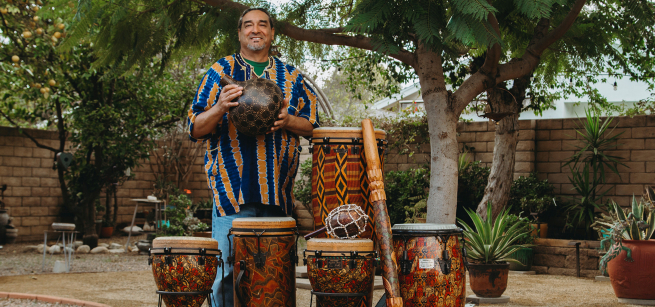 Man standing behind drums and holding one