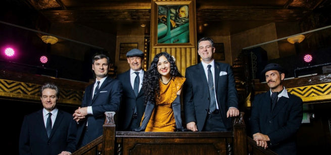 Group photo of the Pepper Moons with all men in suits and lady in yellow dress