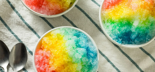 Rainbow shaved ice on a table with spoons
