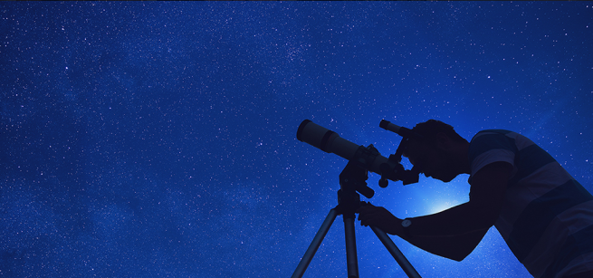 man looking at night sky in a telescope