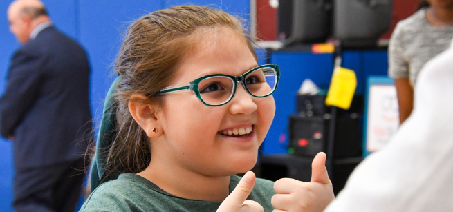 girl with glasses giving the thumbs up sign
