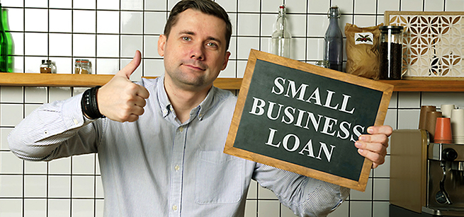 man holds up "small business loan" sign