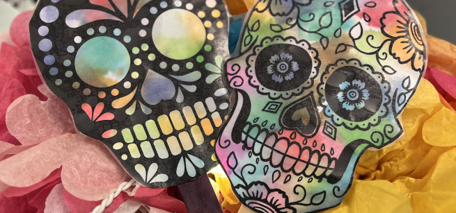 two water colored sugar skulls on popsicle sticks
