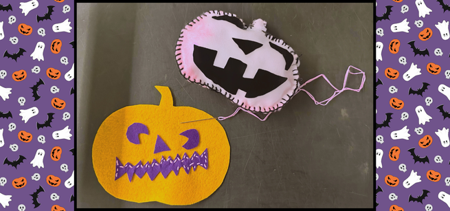 One finished pumpkin pillow plushie and one in process sitting on a table. in the background are cartoon ghosts, bats, and pumpkins