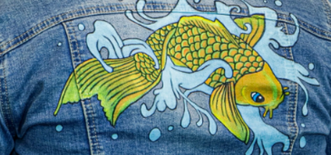 Image of a yellow koi fish with water splashing in the background painted onto a denim jacket