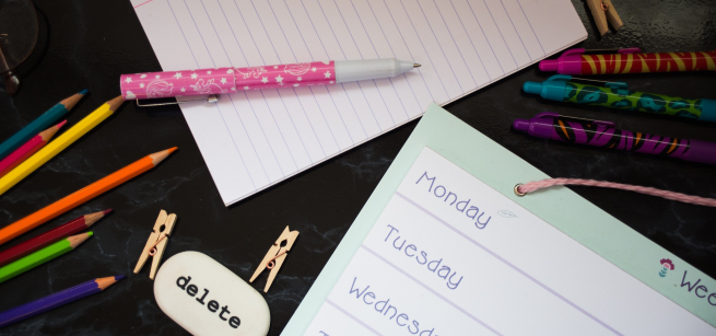 school planner with colored pencils, a pen, a notebook, and eraser