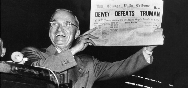 President Harry S. Truman smiles while holding up a newspaper titled "Dewey Defeats Truman"