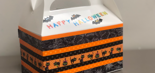 A white favor box decorated with Halloween-themed washi tape is depicted.