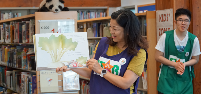 Image of volunteer reading a picture book to children