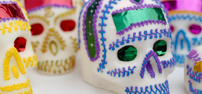 Several sugar skulls brightfly decorated are laid out on a table. 