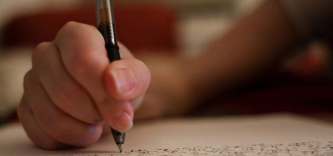 Caucasian person writing, possibly creating, sheet music.