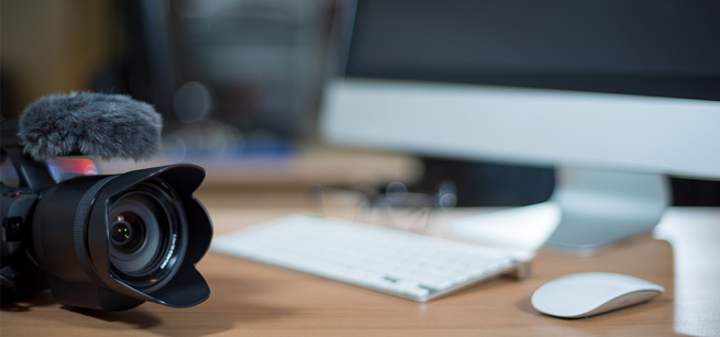 DSLR camera on top of a desk next to a computer