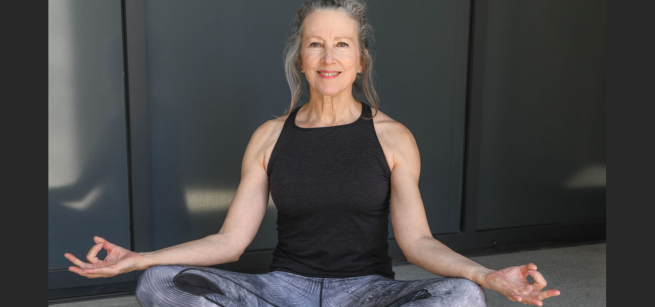 Kate O'Neal seated in a Yoga pose smiling.