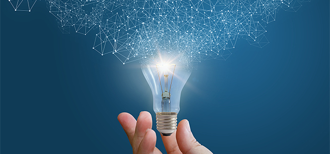 A hand holds a lightbulb with an array of polygons floating out of the top