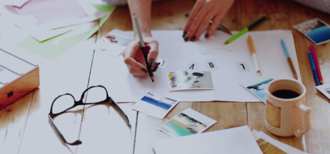 a woman's hands are shown writing on a poster board with photographs and scrap book pieces