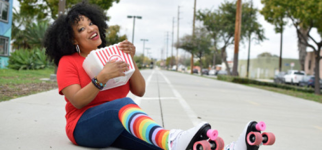 Kymberly Stewart radiates joy and fun with a red and white stripe popcorn box, rainbow striped socks and roller skates with pink wheels