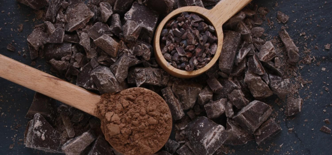 Picture of cacao beans being scooped up by spoons.