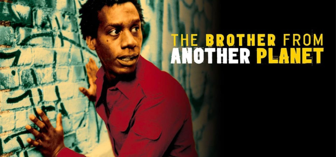 A young man is shown alert against a graffiti'd brick wall