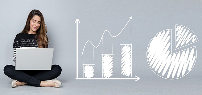 Woman sits with a laptop with drawn image of pie chart and bar graph to the side.