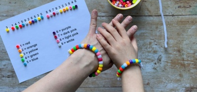 hand wearing bracelet, cup of beads, beading guide