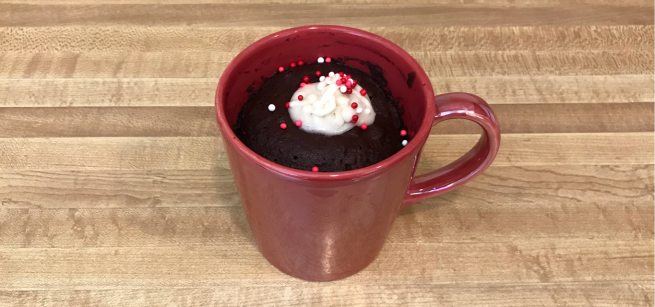 A mug cake in a red mug, topped with whipped cream