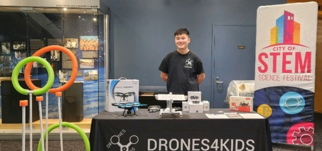 Man standing behind a table with drones