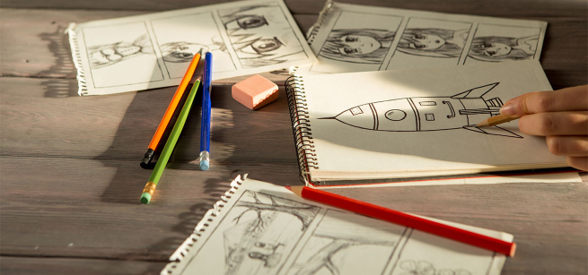 Close-up of hand drawing several black and white graphic and comic storyboards using a sketch pad and pencils.