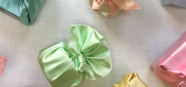 Examples of folded Bojagi cloth in the colors green and pink.