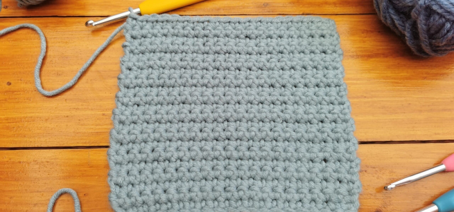 gray color knitting sample with knitting needles on the side