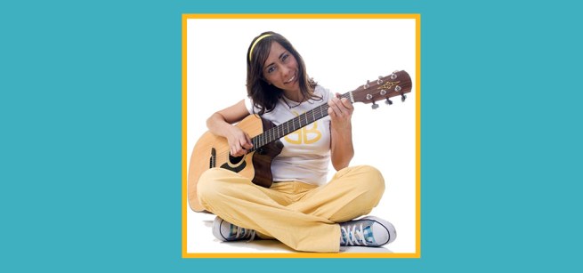 woman sitting cross legged with an acoustic guitar