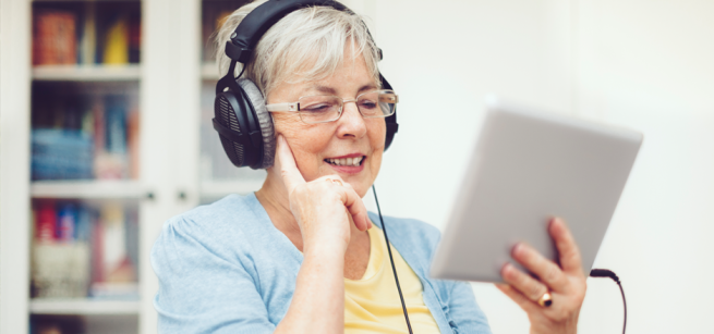 Woman holding tablet and wearing headphones.