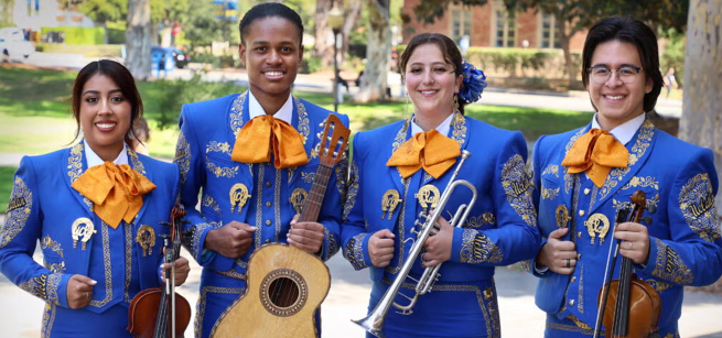 Four young adults dressed in colorful dress and holding instruments