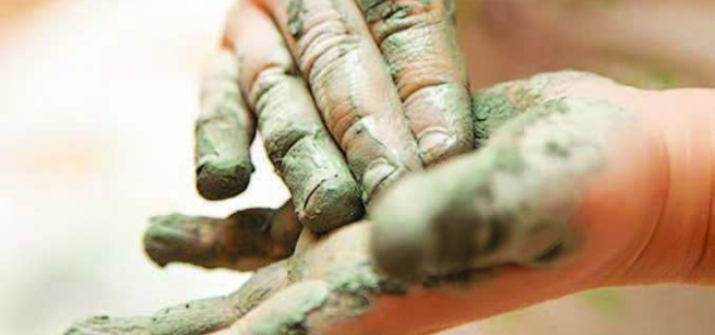 child's hands covered with clay