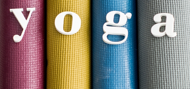 Rolled yoga mats in different colors with letters that spell yoga