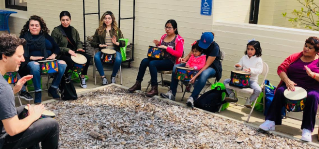 A teacher showing adults and children how to play drums.