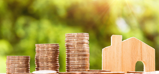  Coins next to wooden picture of a house